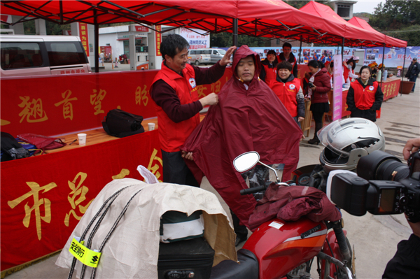 梧州市總工會(huì)的黨員義工們?cè)谑袞|出口春運(yùn)服務(wù)站助力“摩托大軍”平安返鄉(xiāng)，幫助他們檢查車輛和行李，穿上雨衣。--黃賀峰攝.j